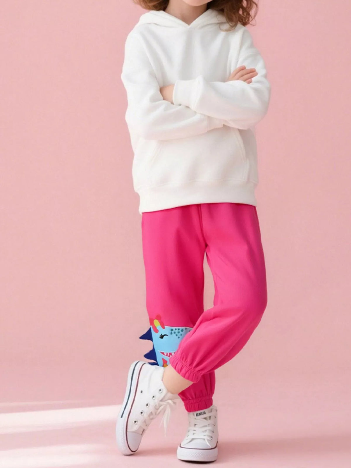 Bright pink dinosaur-applique joggers on a child