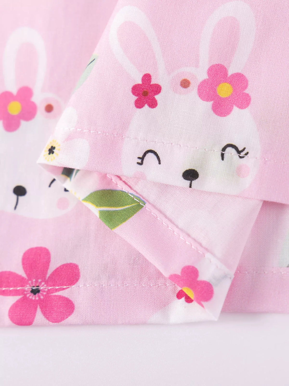 White bunny faces and flowers on pink fabric