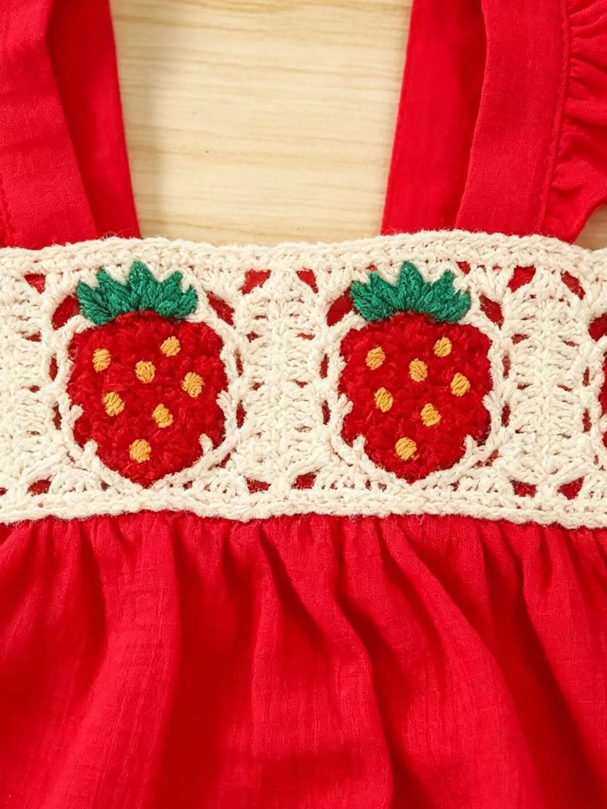 Crochet strawberry motifs across the cream band