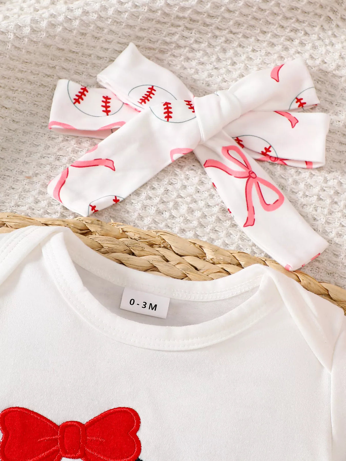 Baseball-print bow headband above white neckline