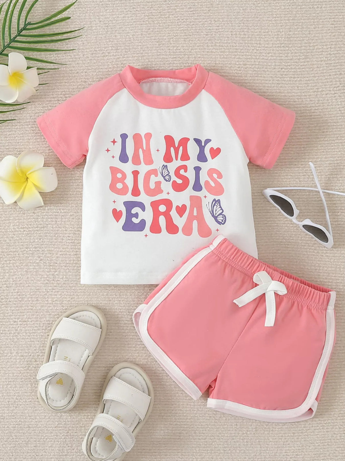 White Big Sis graphic tee with pink raglan sleeves and shorts laid flat