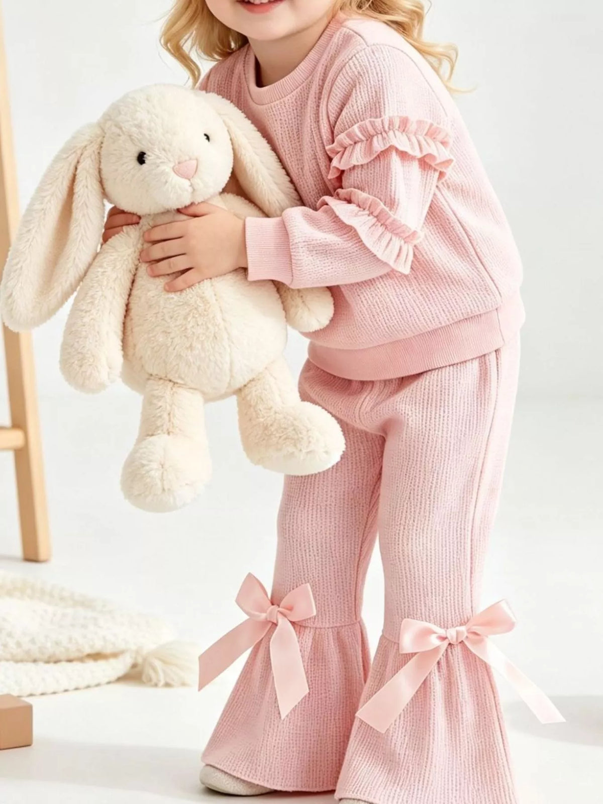 Pink outfit on a child holding a plush bunny