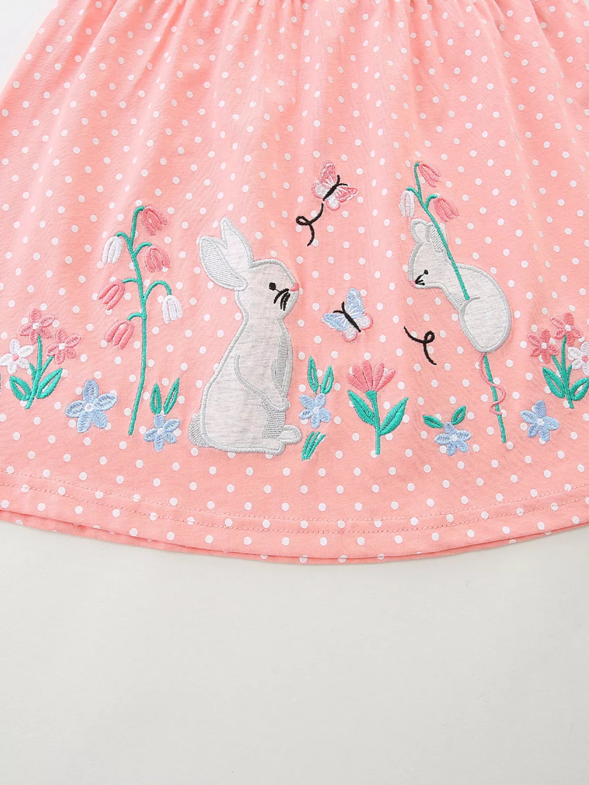 Bunnies and flowers near the dotted skirt hem