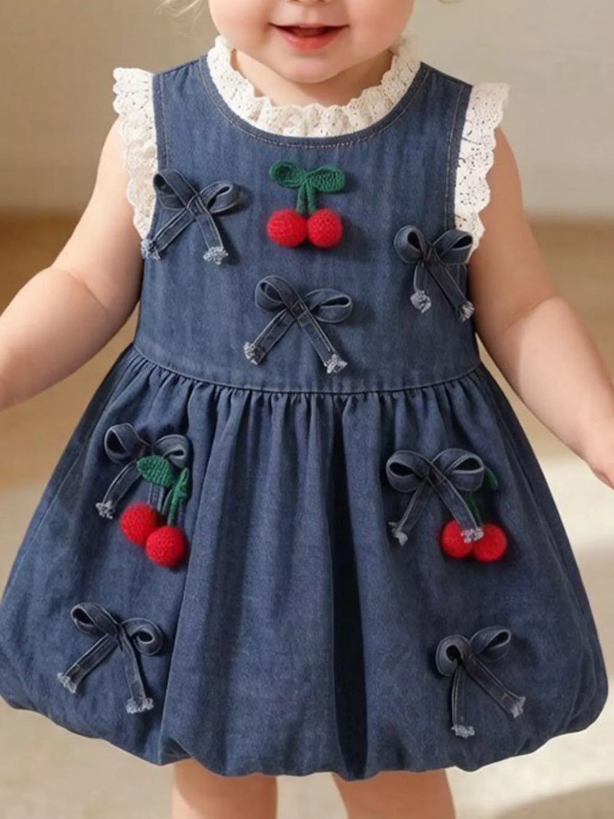Denim cherry-applique dress with lace trim and small bows on a child