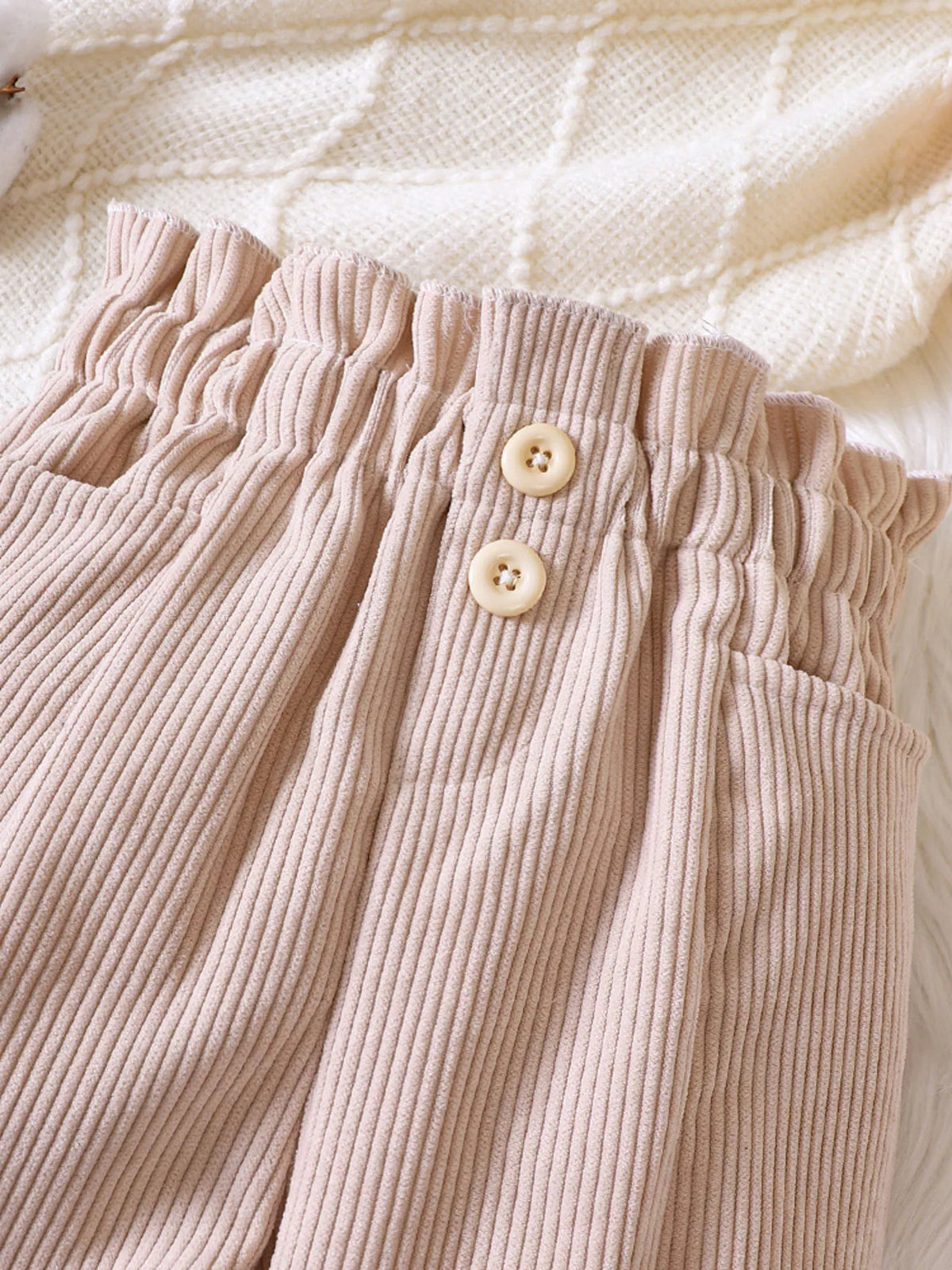 Two buttons on the beige corduroy waistband