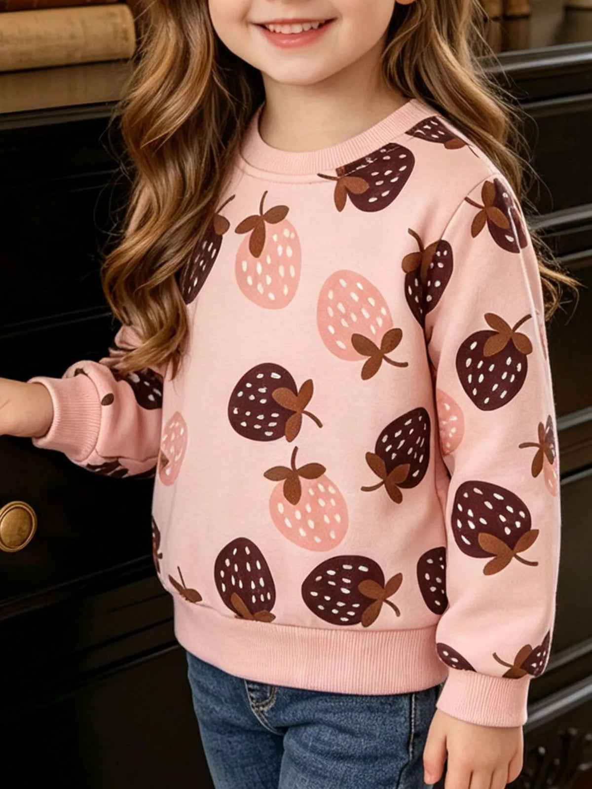 Pink strawberry-print crewneck sweatshirt on a child