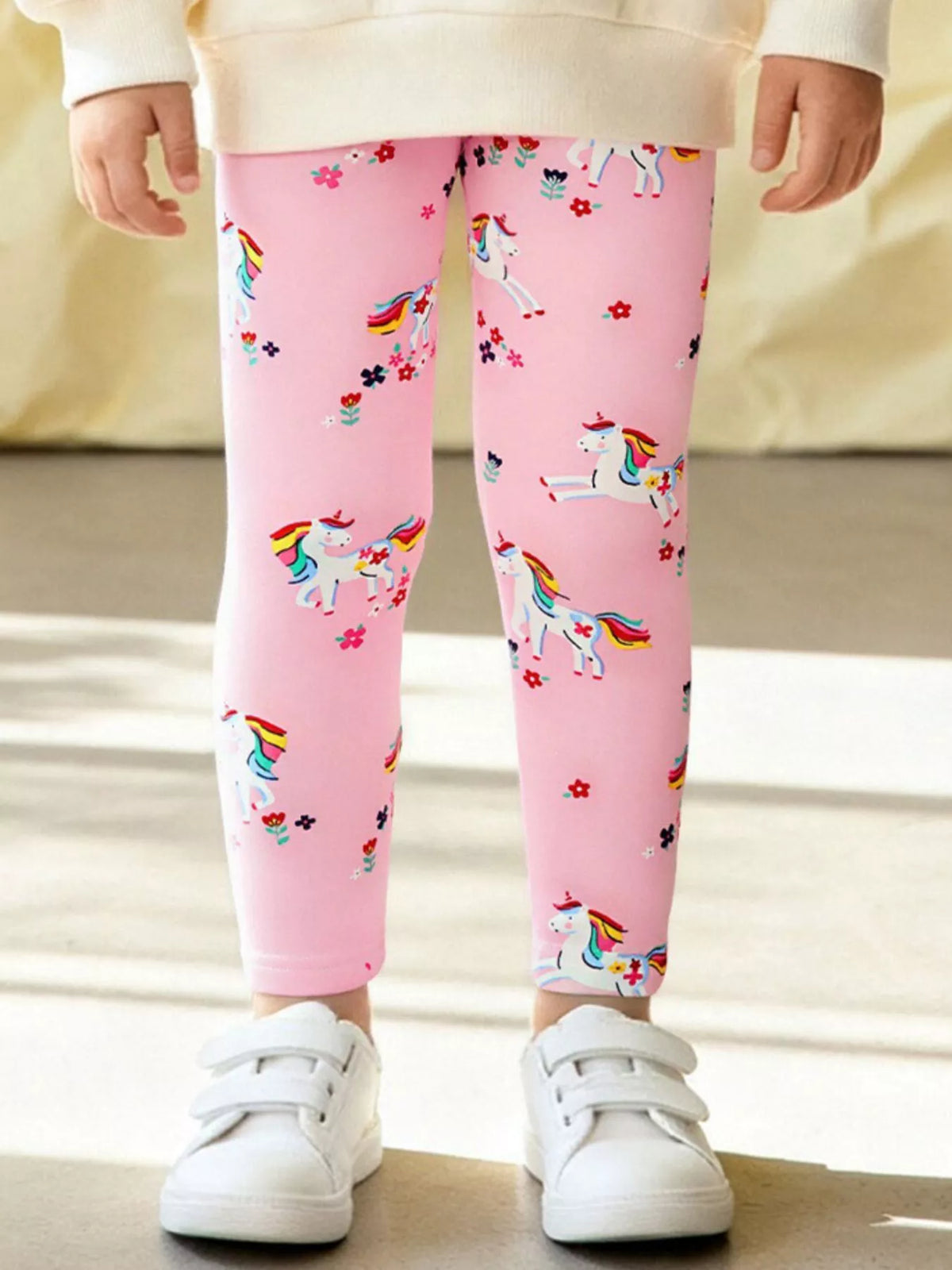 Pink unicorn-and-flower print pants on a child