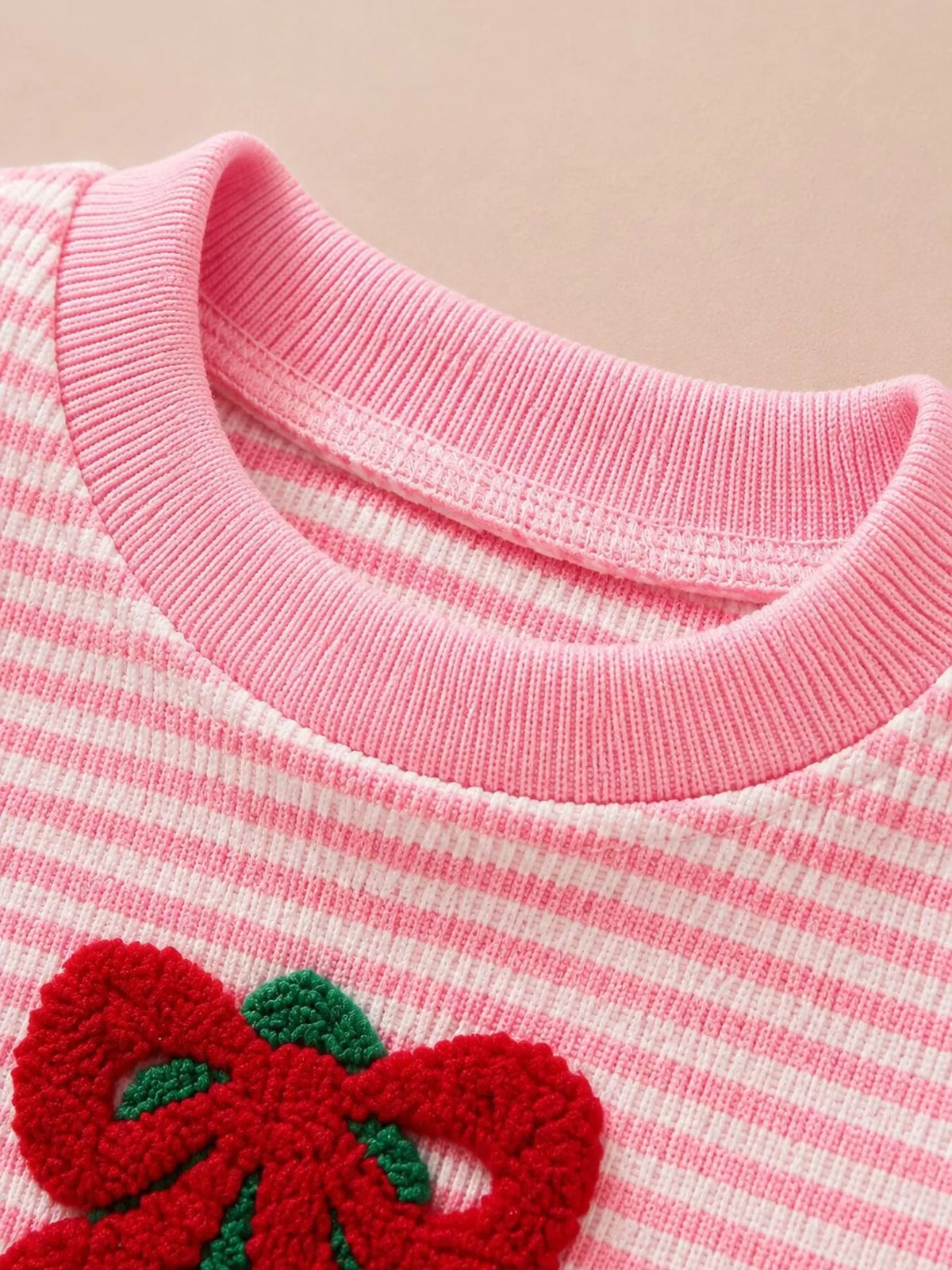 Pink ribbed neckline and red bow above tree applique