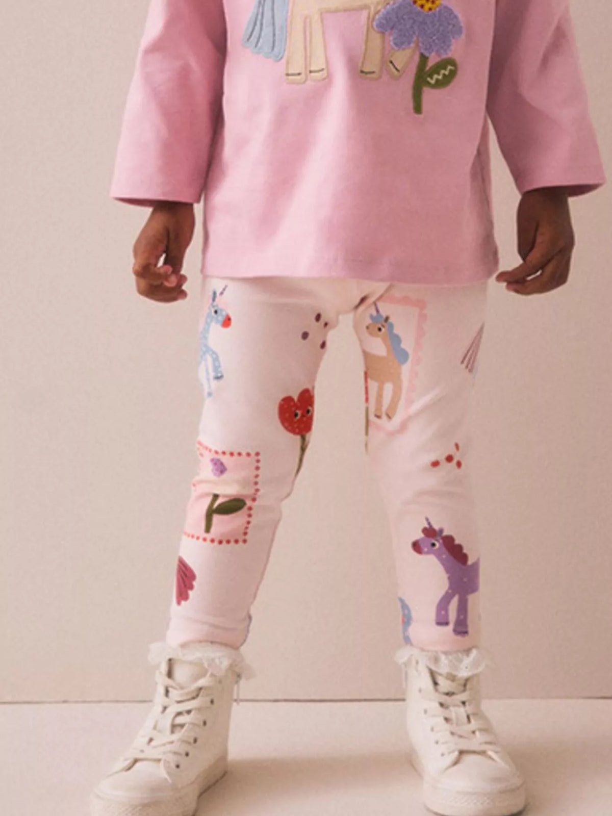 Pink unicorn-and-flower print leggings on a child