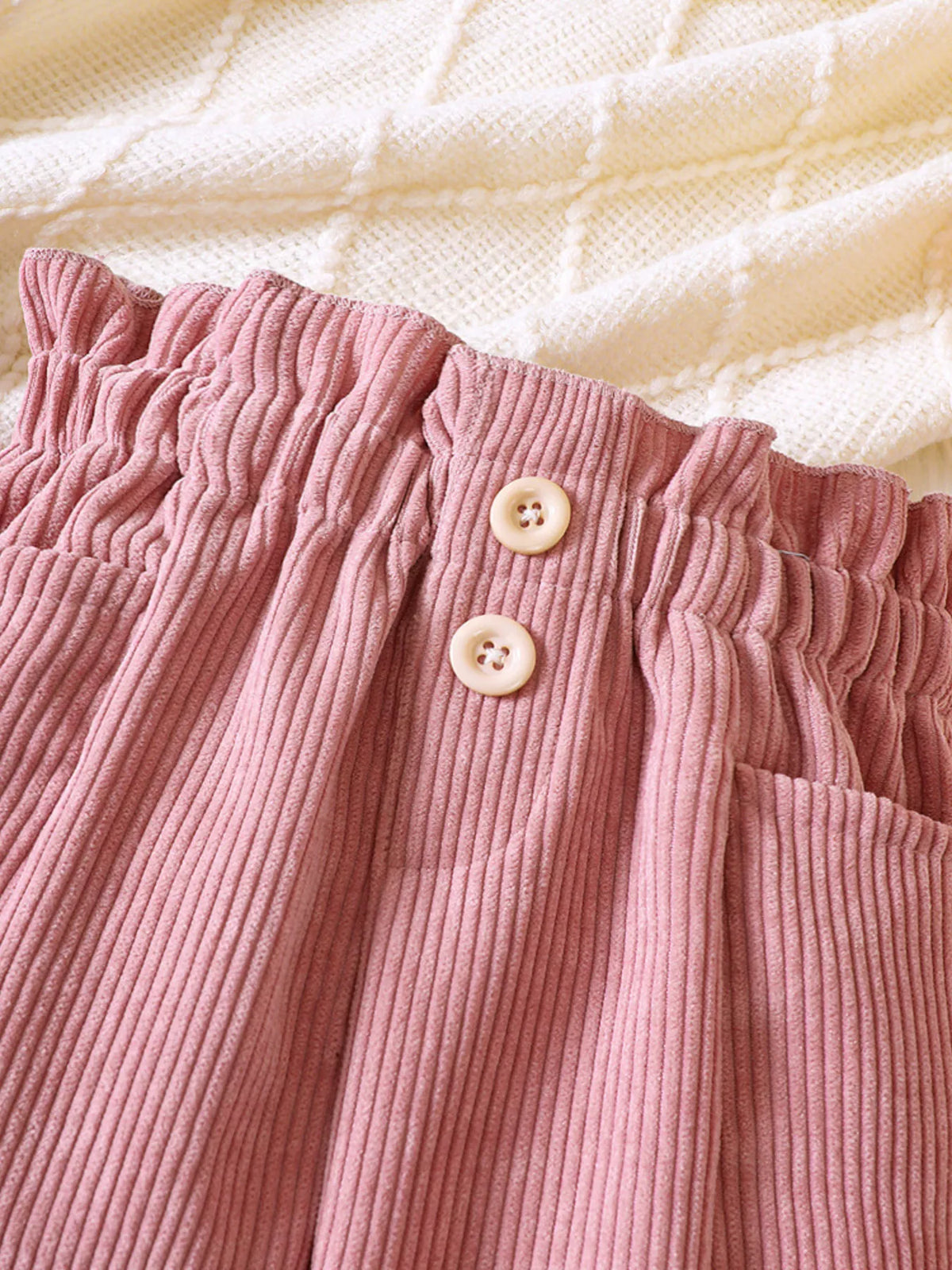 Two buttons on the pink corduroy waistband