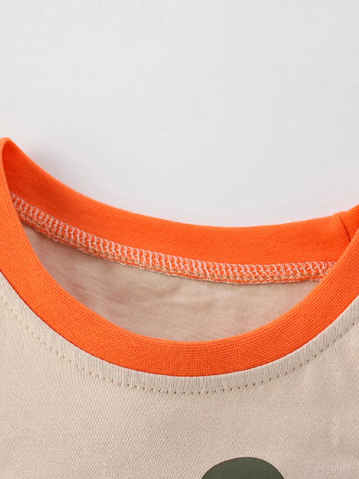 Beige dinosaur patch pocket shirt — round neckline with orange inner tape