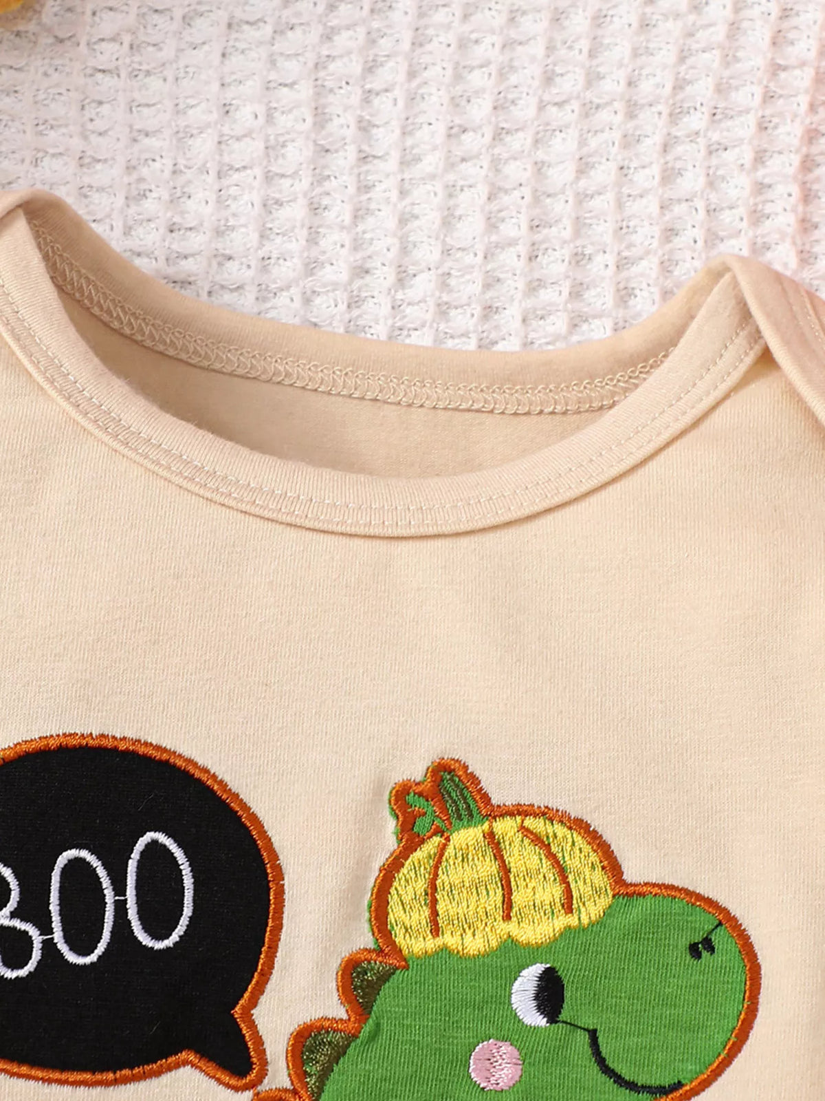 Cream envelope neckline and green dinosaur motif