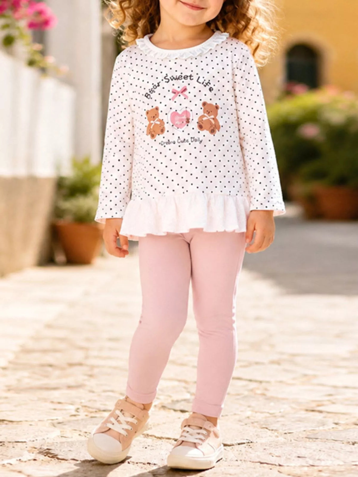 White polka-dot bear ruffle top with pink leggings on a child
