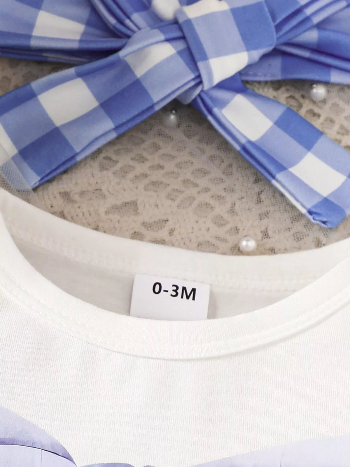 Blue gingham bow headband above white neckline
