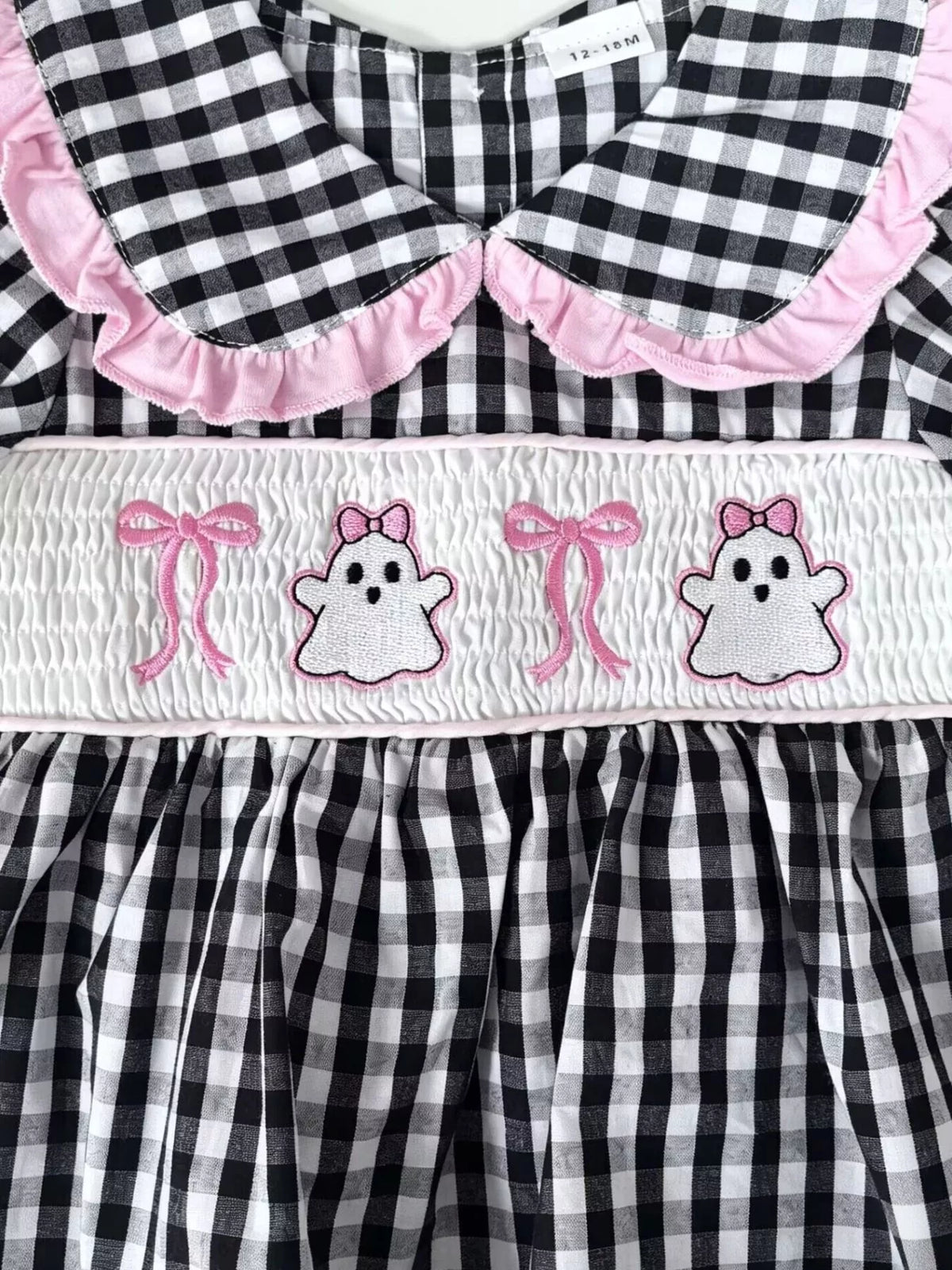 Pink-edged rounded collar above ghost-and-bow embroidery