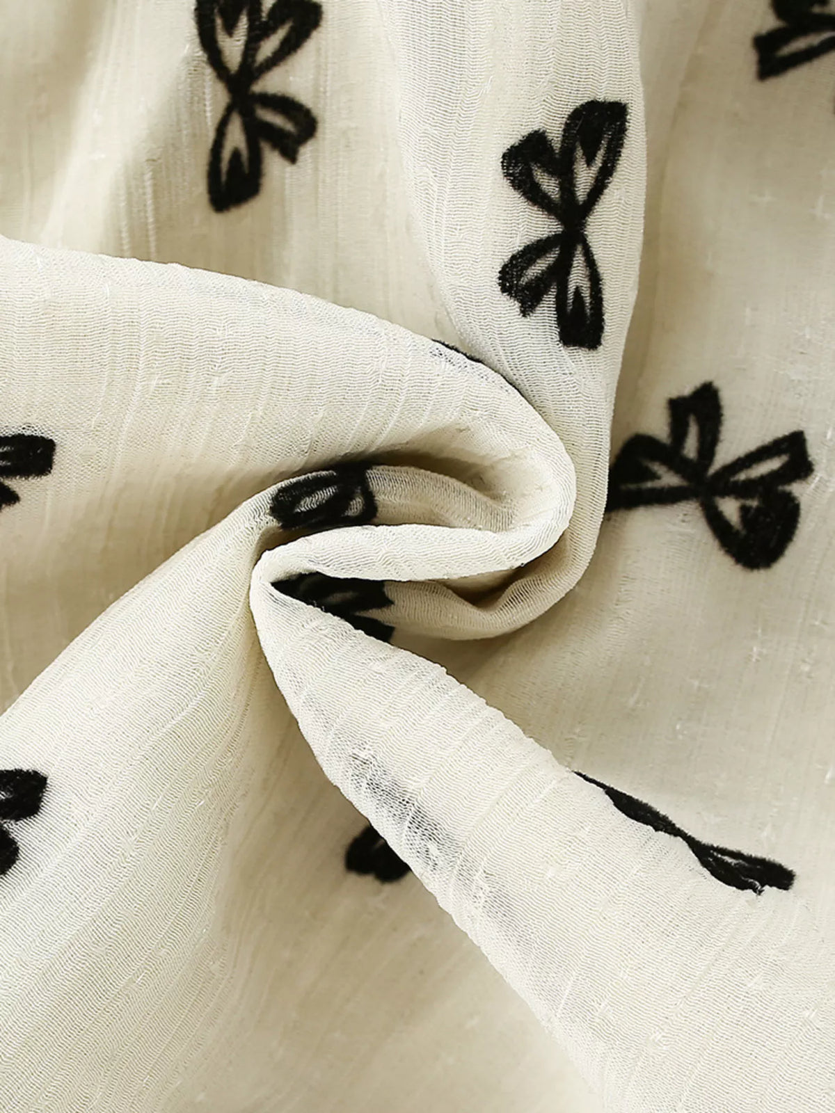 Small black bow motifs on cream fabric