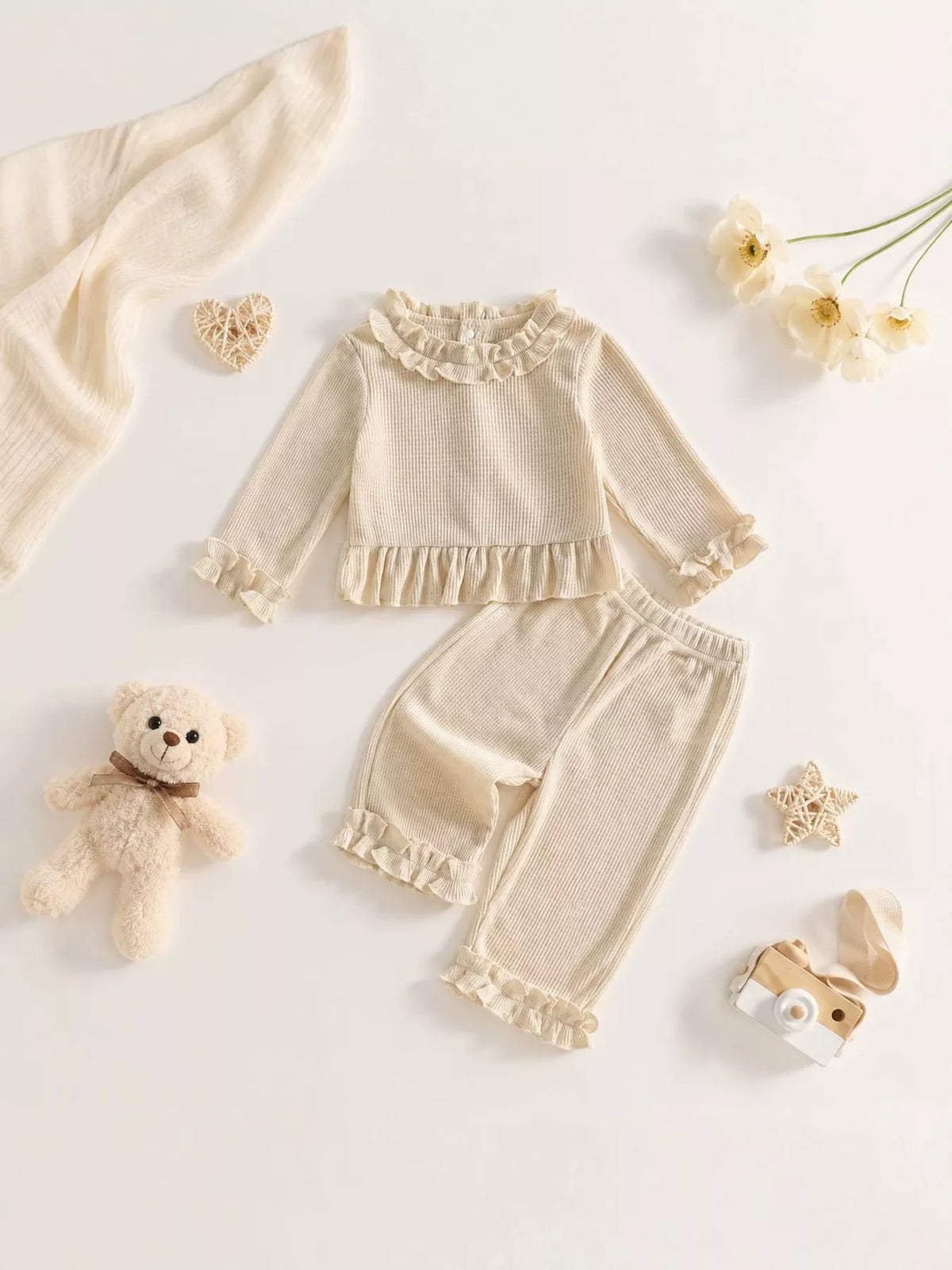 Cream ruffle-trimmed top and pants laid flat