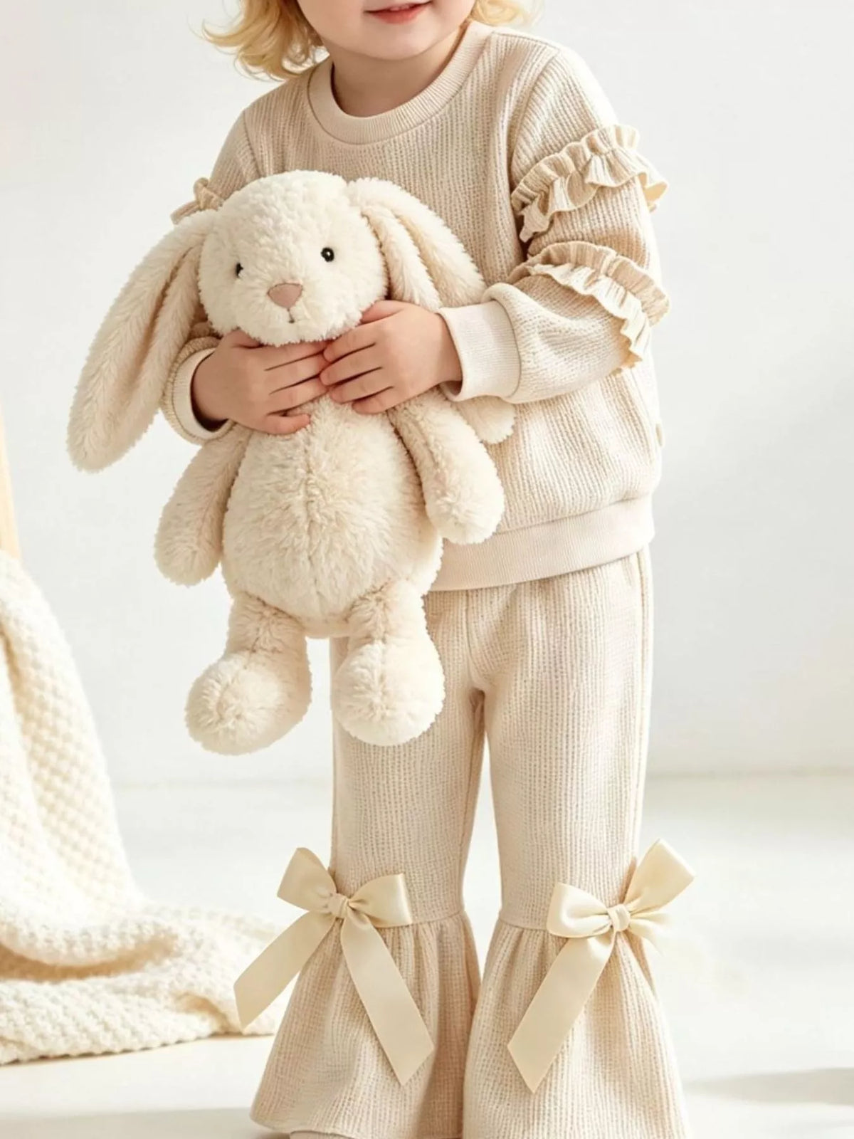 Cream outfit on a child holding a plush bunny