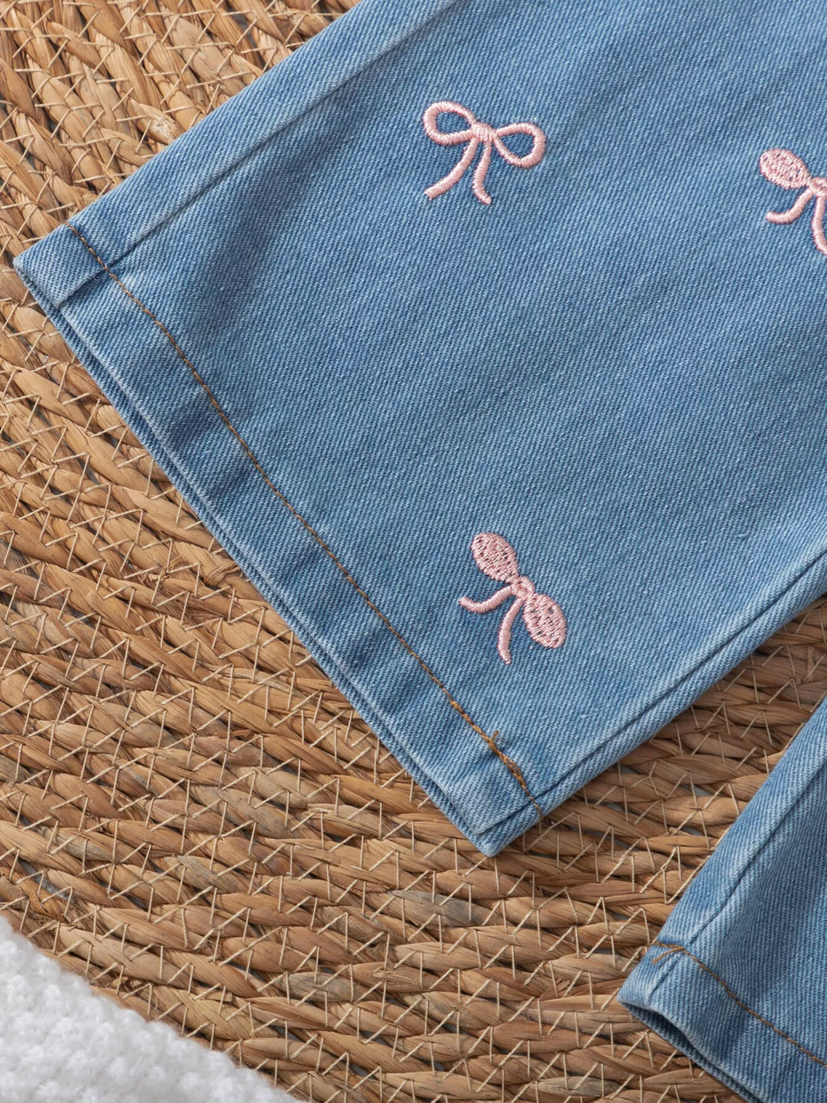 Pink embroidered bows above the wide denim hem