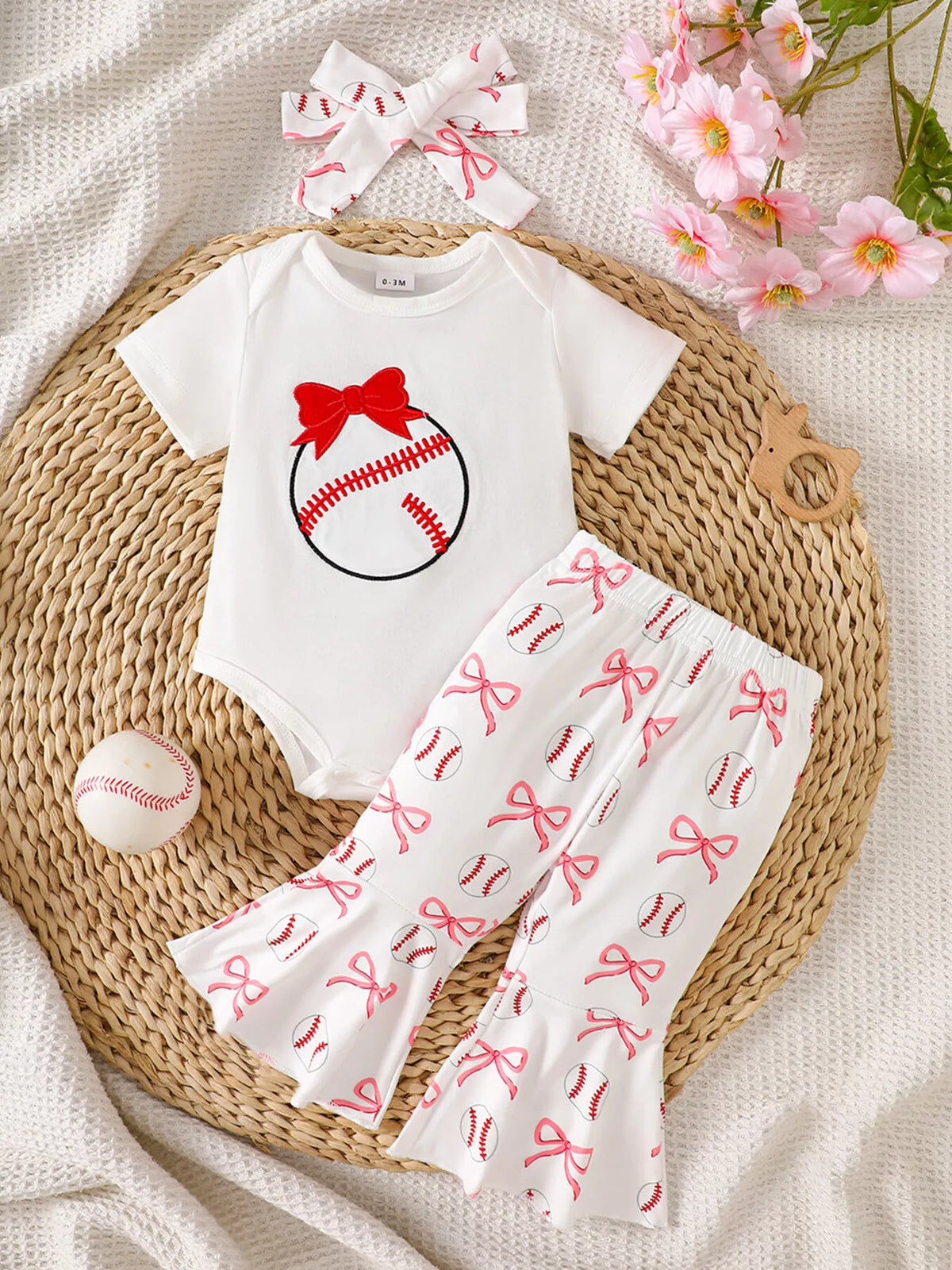 White baseball-and-bow bodysuit with printed flared pants and headband laid flat