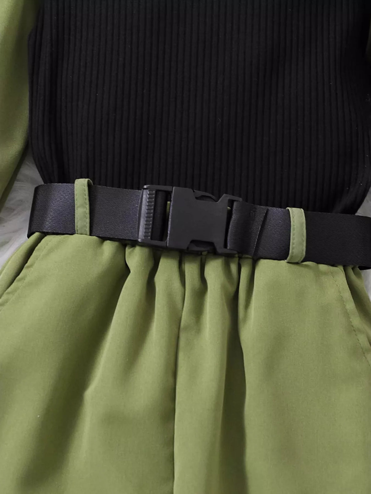 Black buckle belt above the green waistband