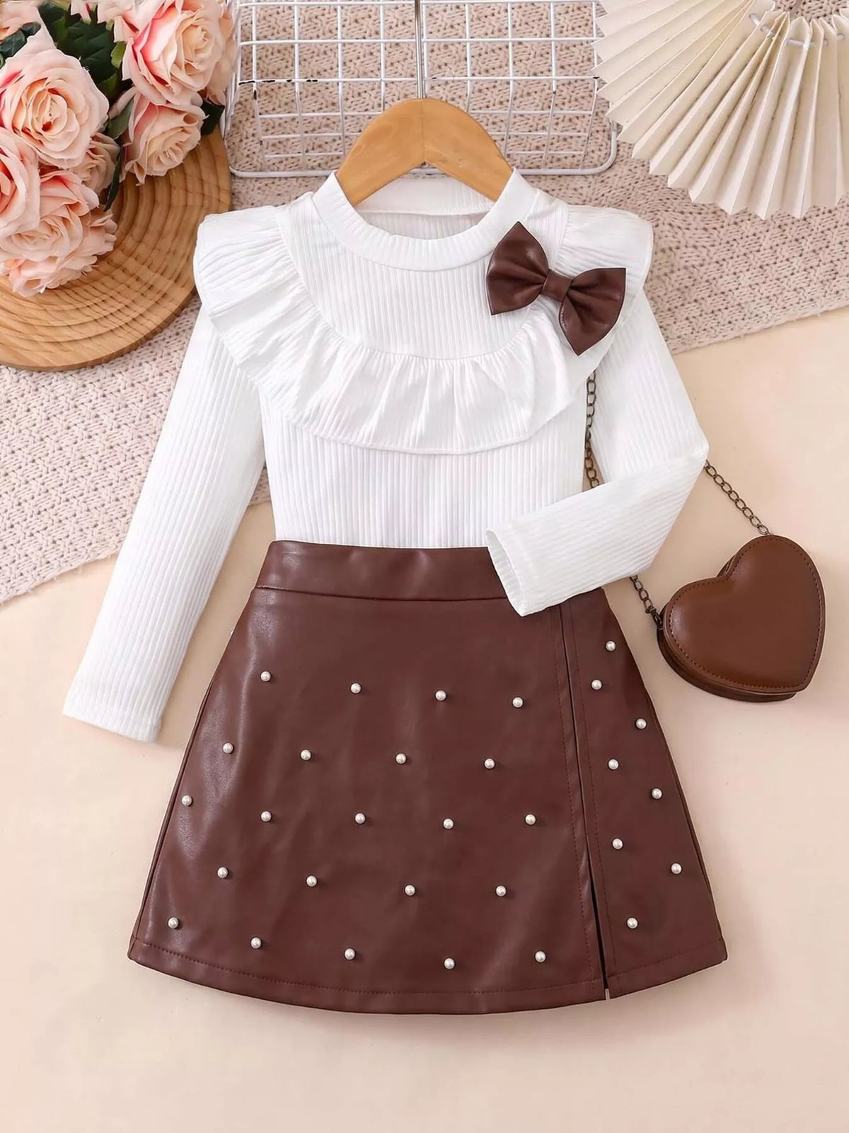 Outfit laid flat beside a heart-shaped bag