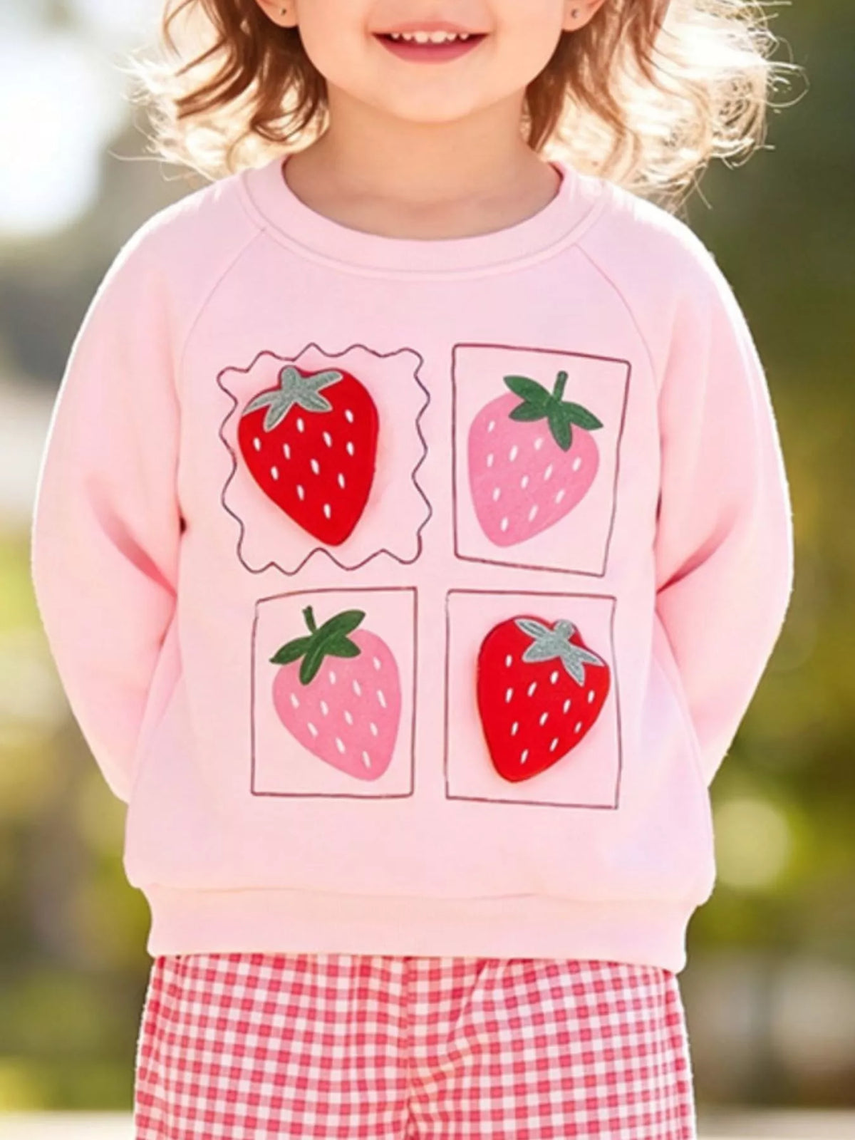 Four strawberry motifs on the pink sweatshirt