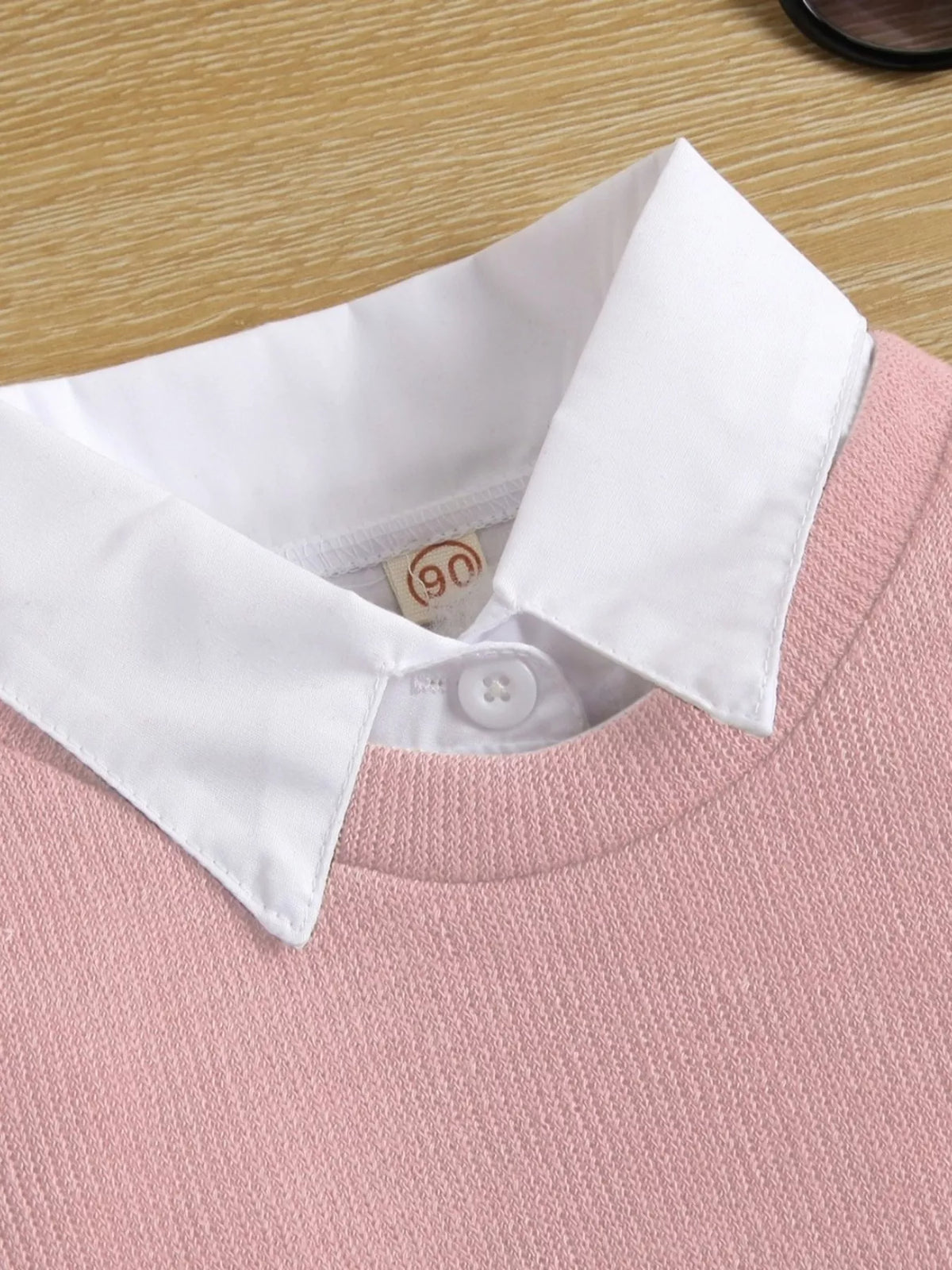 White pointed collar above the pink knit neckline