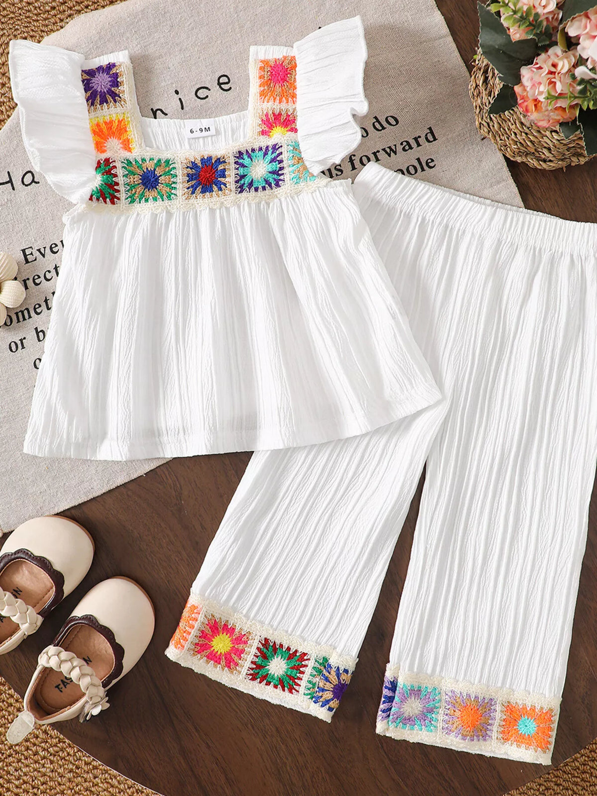 White crochet-trimmed top with wide-leg pants laid flat