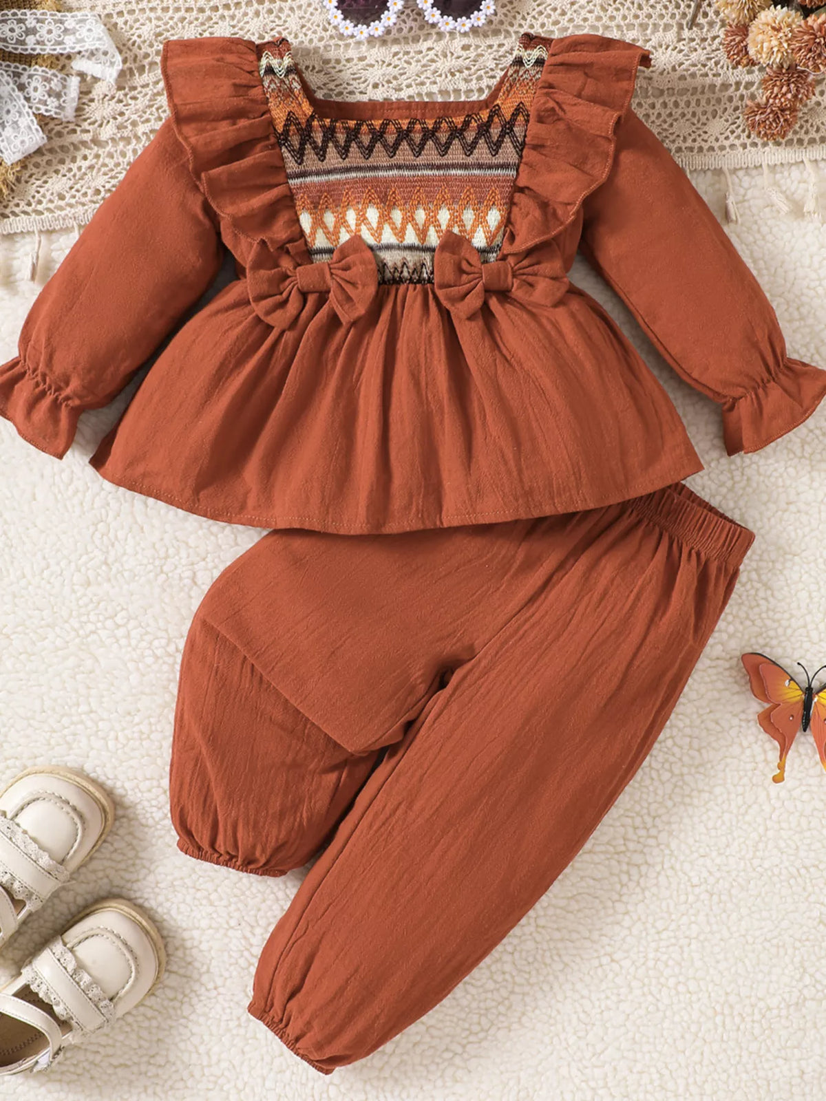 Rust ruffle-trimmed patterned-yoke blouse with matching pants laid flat
