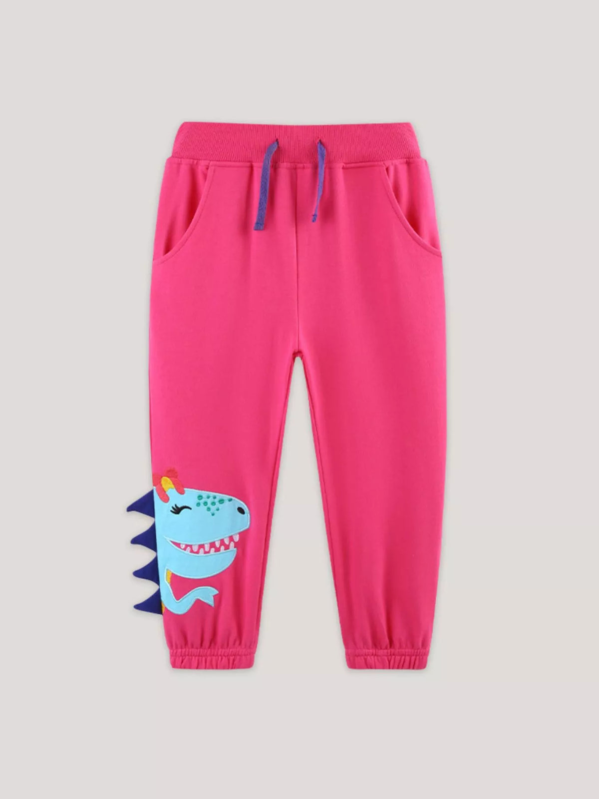 Bright pink dinosaur-applique joggers laid flat