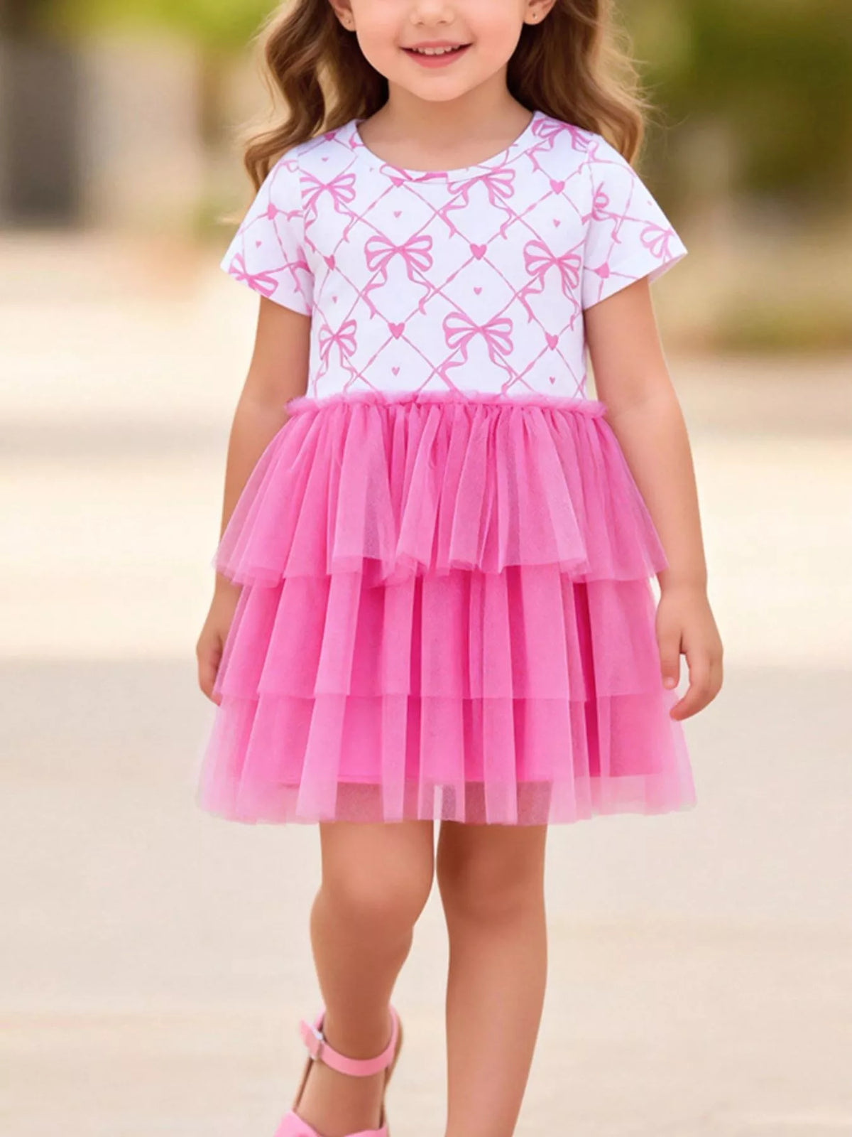 White bow-print dress with a tiered bright pink tulle skirt on a child
