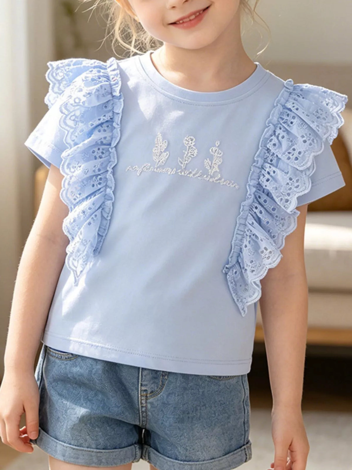 Light blue tee with eyelet shoulder ruffles on a child