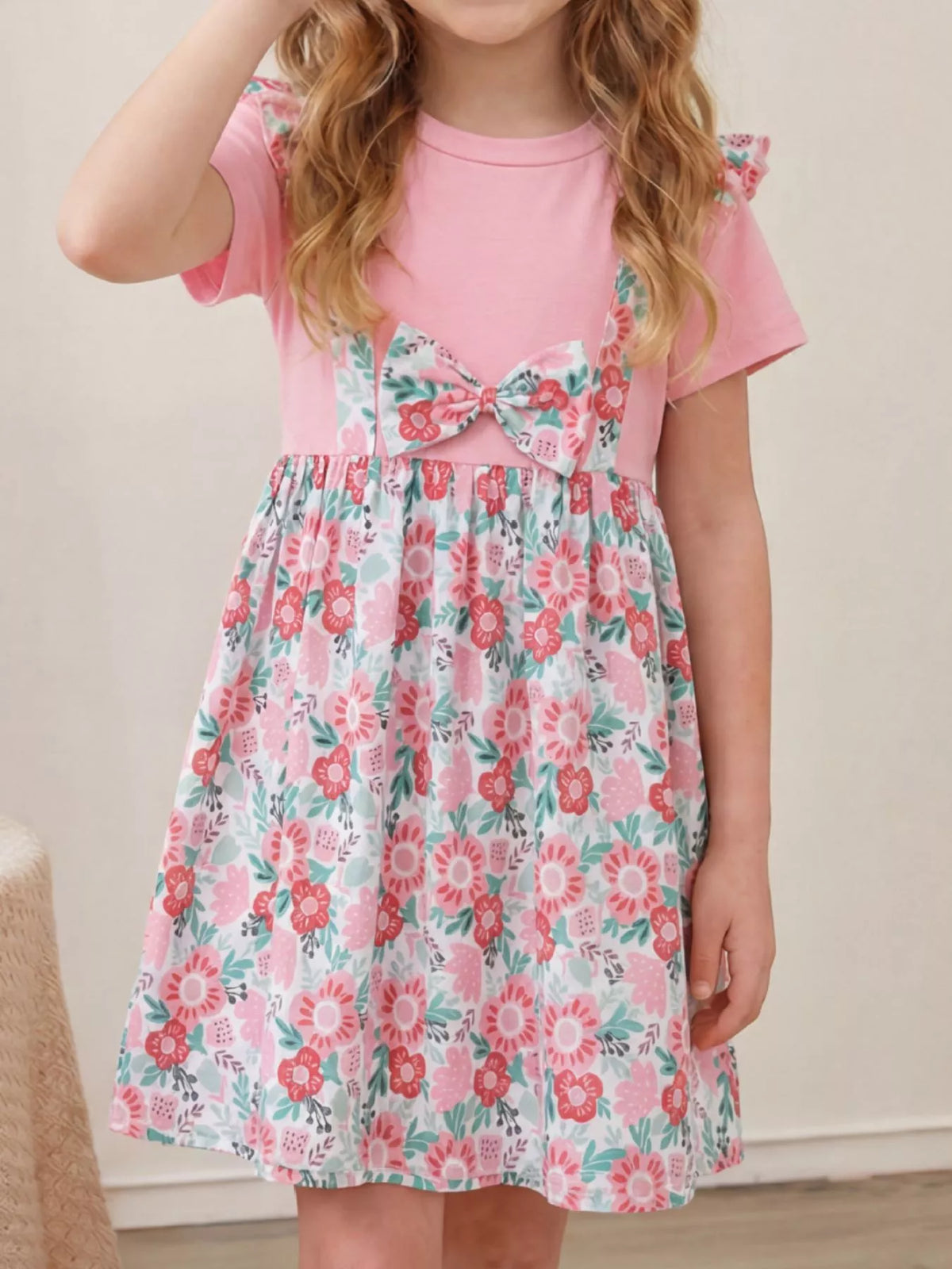 Pink short-sleeve dress with floral trim, a waist bow and floral skirt on a child