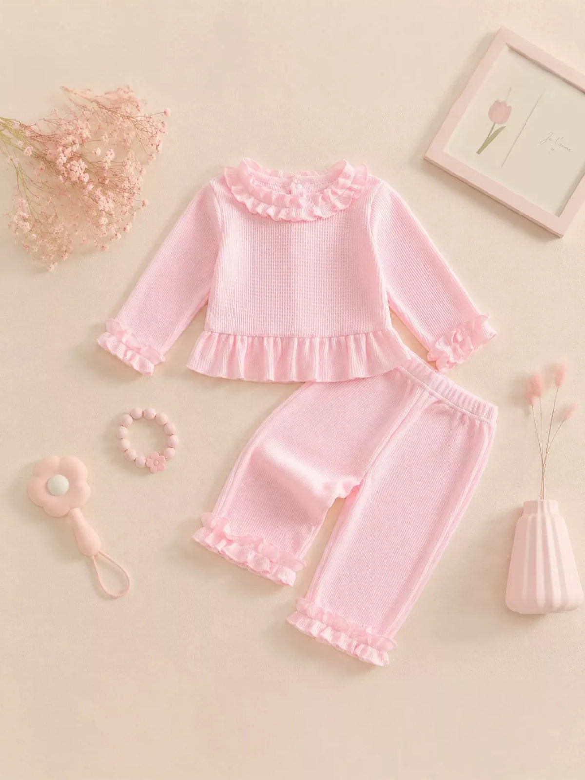 Pink ruffle-trimmed top and pants laid flat