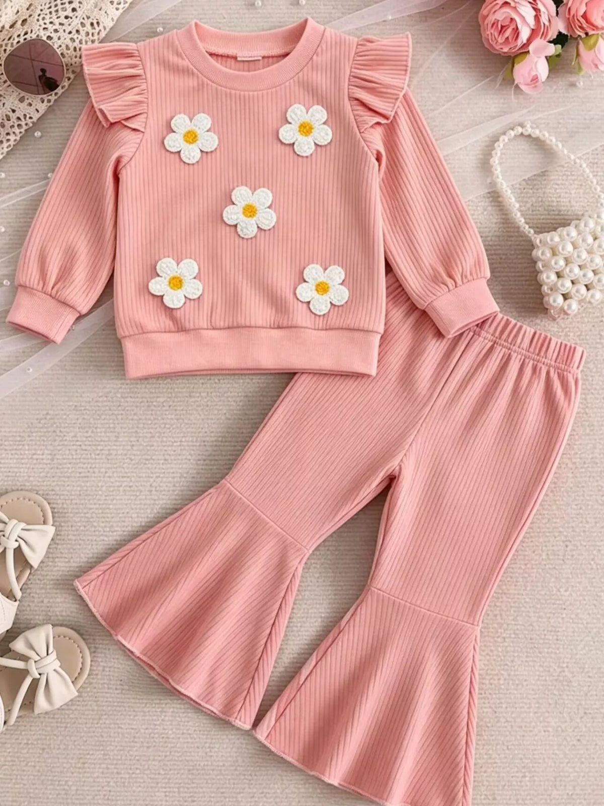 Pink ribbed daisy-applique ruffle top with flared pants laid flat