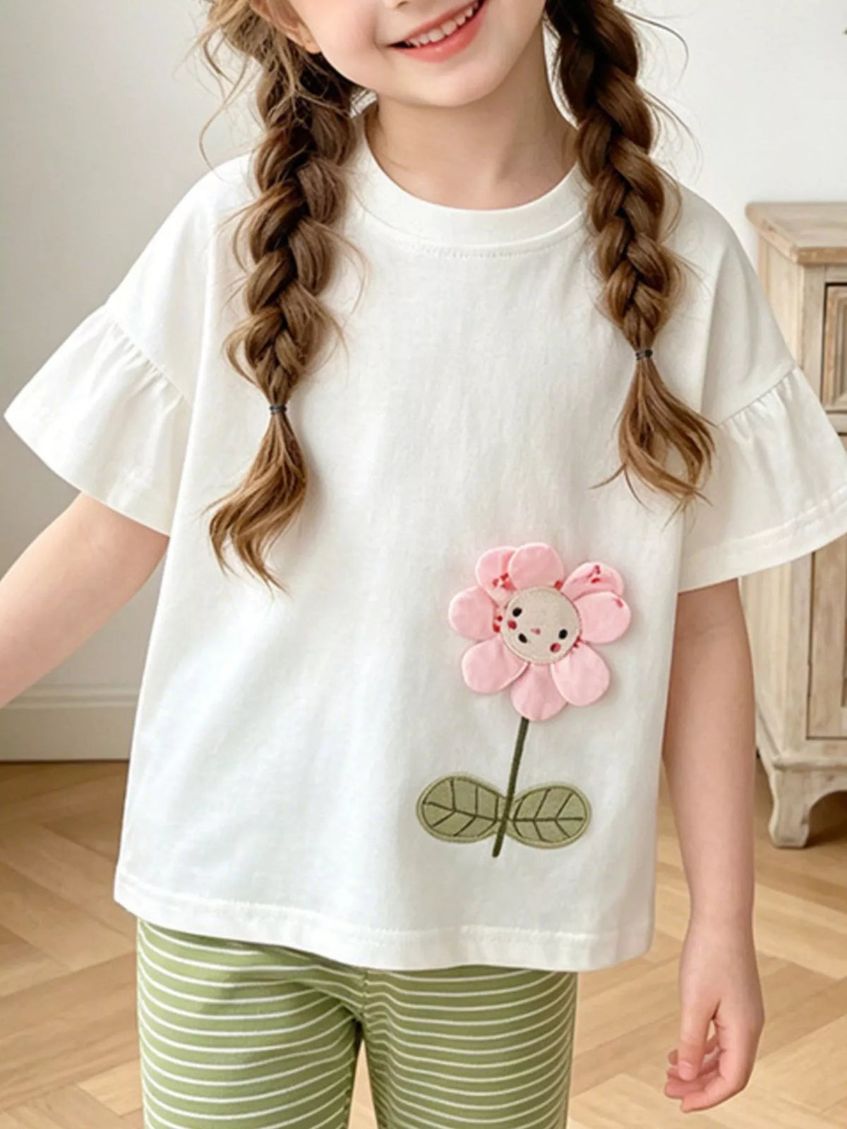 White flower applique ruffle sleeve top and green striped leggings — outfit shown on child