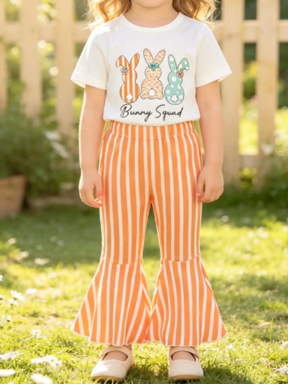 White bunny tee with orange striped flared pants on a child