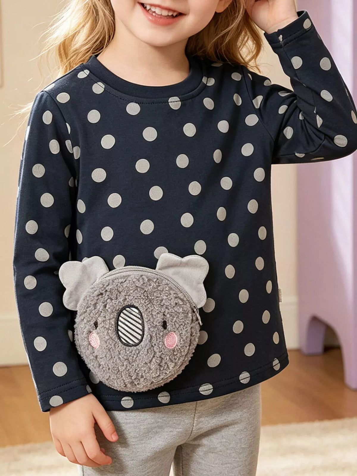 Black polka-dot long-sleeve top with a plush koala pocket on a child