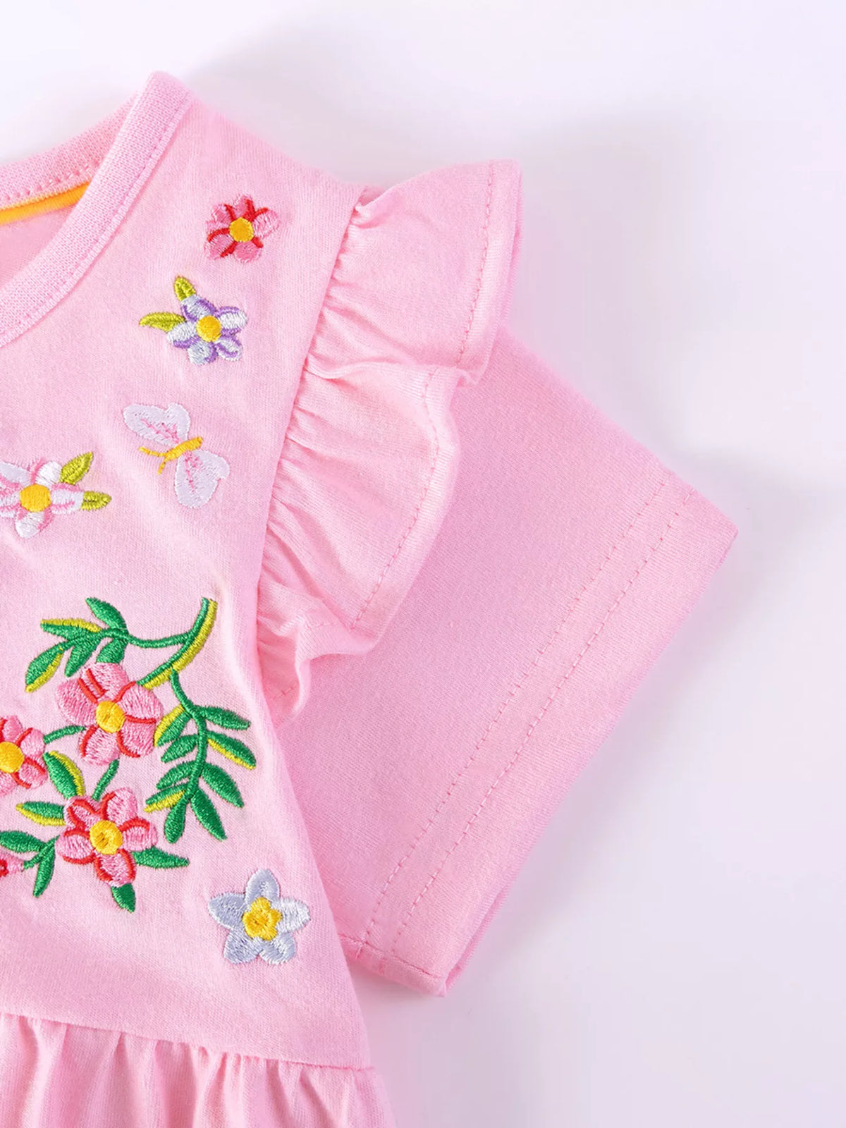 Pink shoulder ruffle beside embroidered flowers