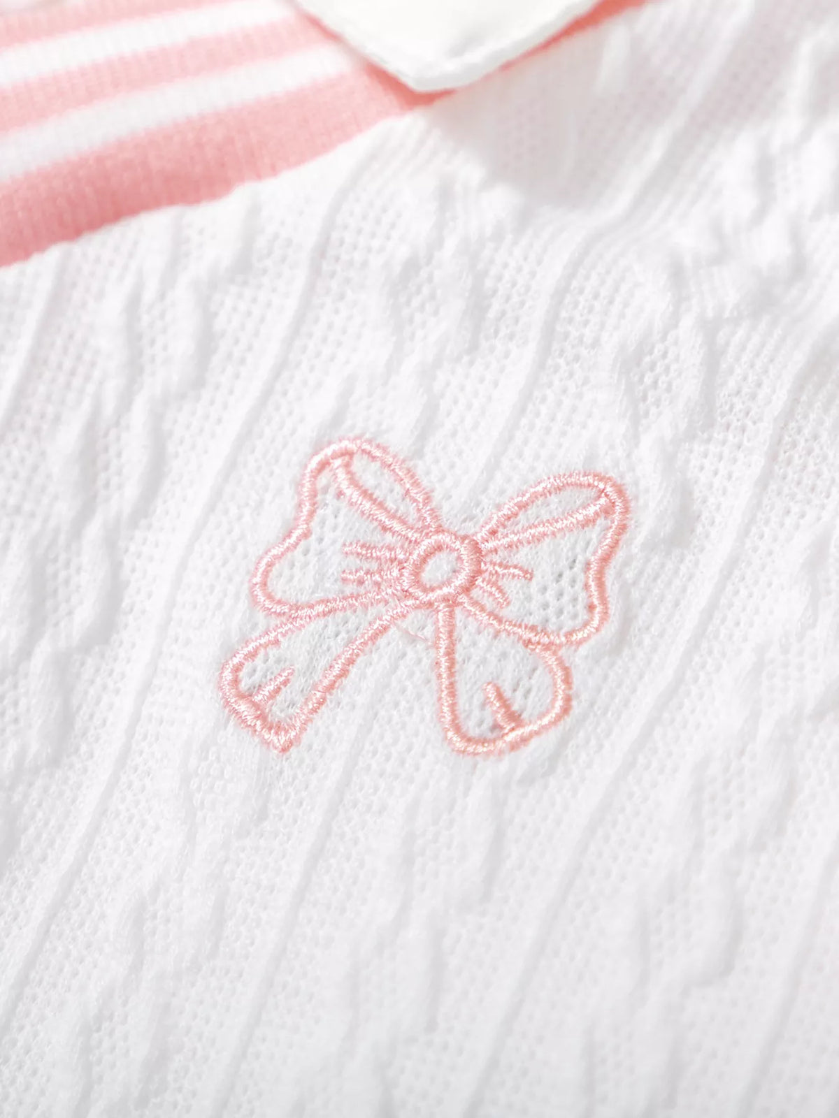 Pink embroidered bow on white cable-textured fabric