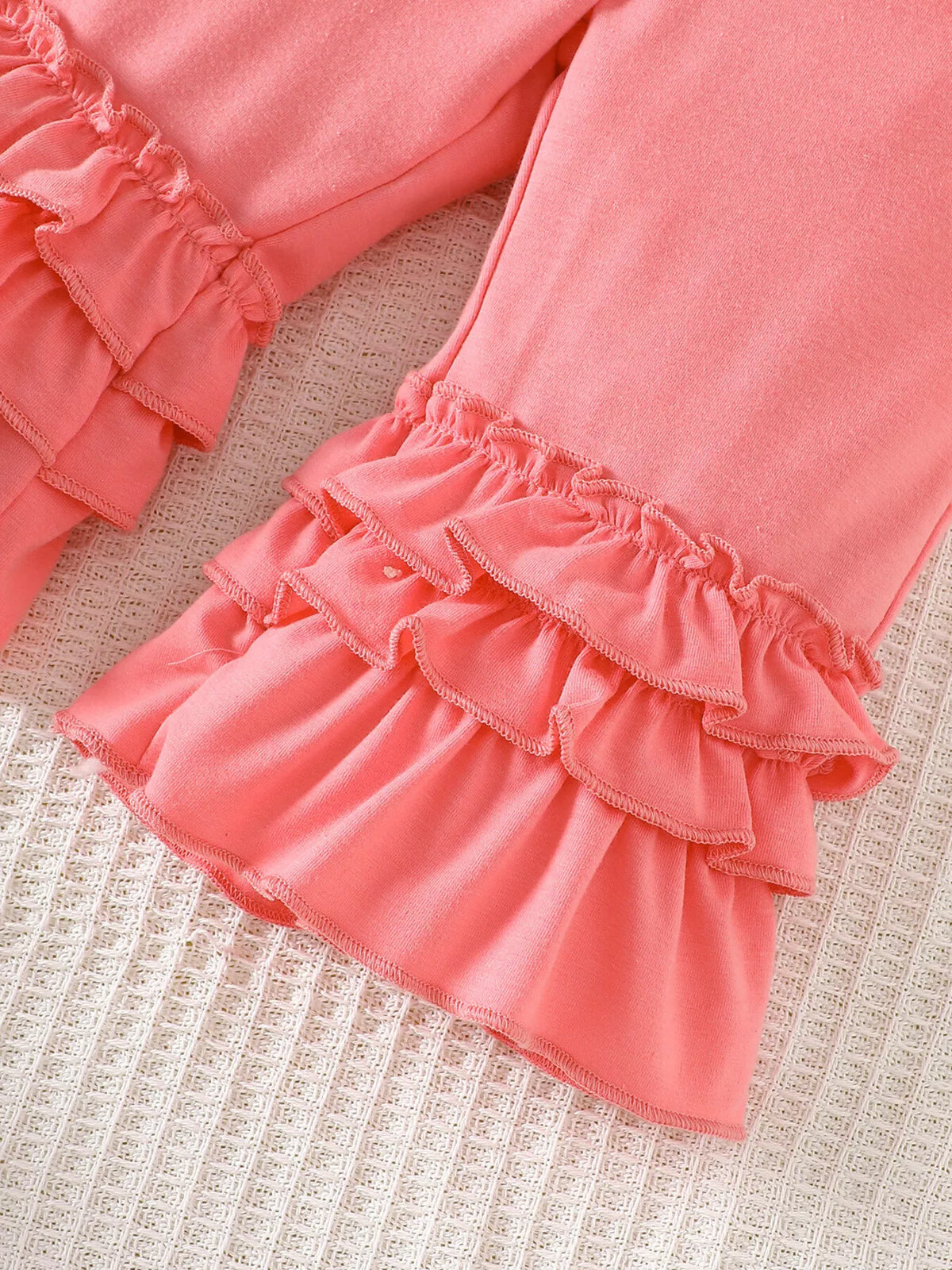 Layered pink ruffles at the pant hems