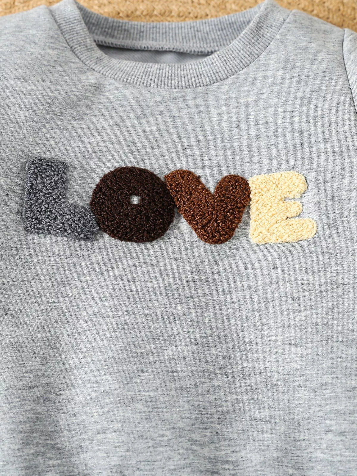 Multicolored textured Love applique on gray fabric