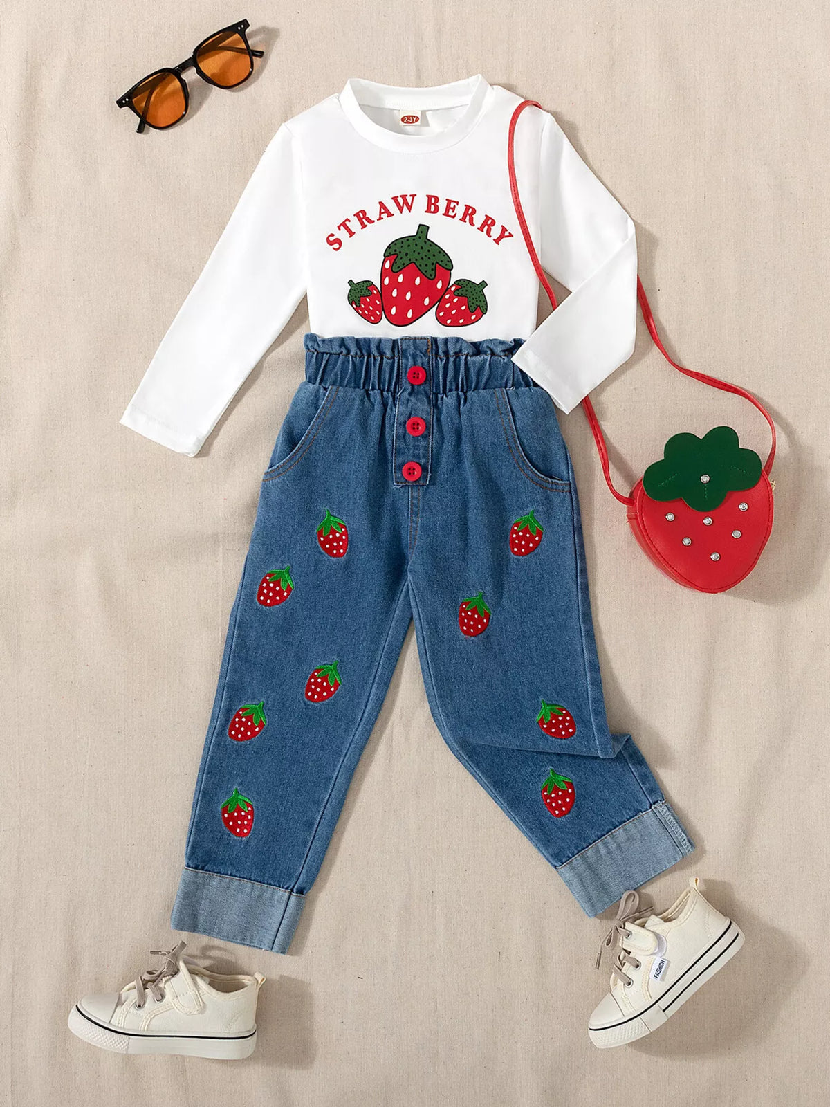 Outfit laid flat beside a strawberry-shaped bag