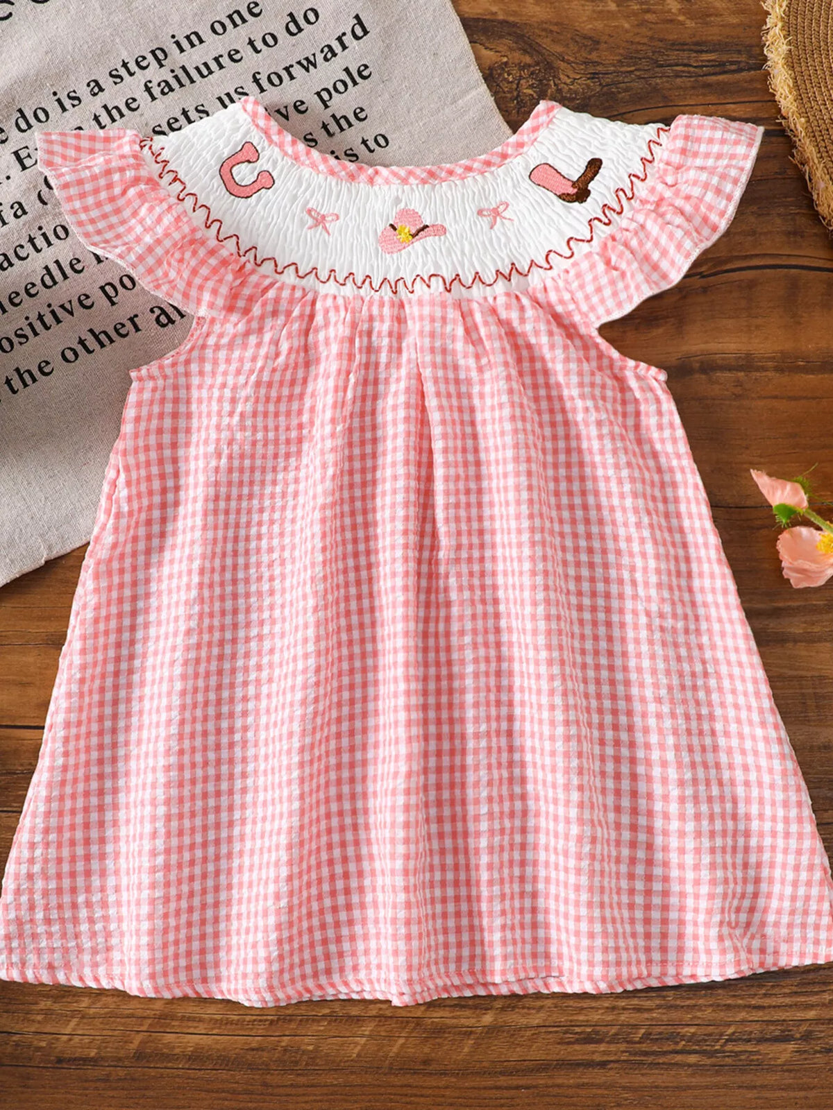 Pink gingham smocked dress with shoulder ruffles laid flat