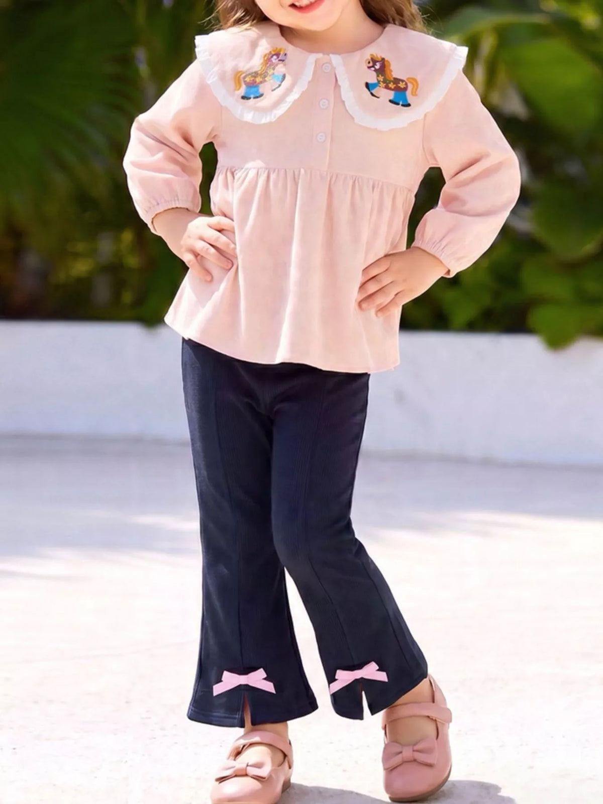 Peach pony-collar peplum top with navy bow-trimmed flared pants on a child