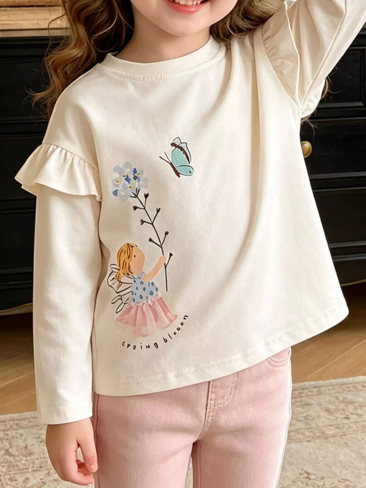 Cream fairy-graphic long-sleeve top with shoulder ruffles on a child