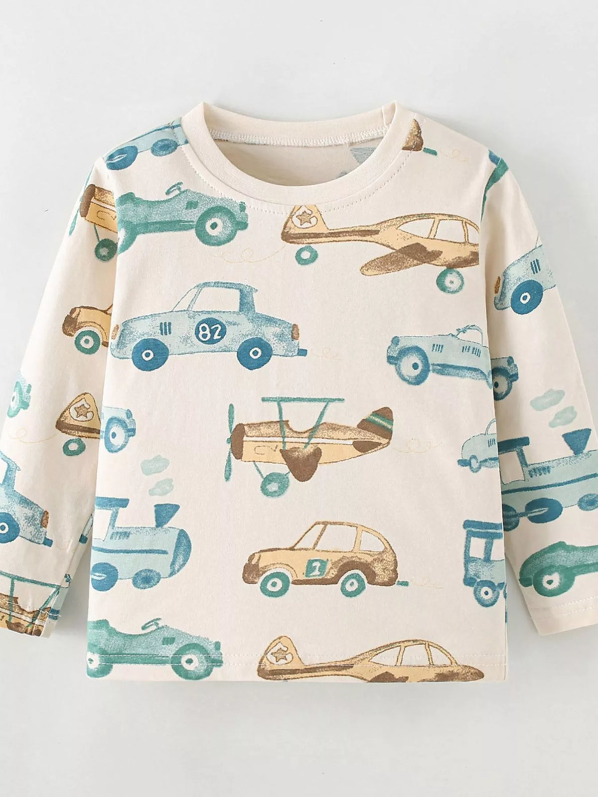 Cream long-sleeve tee with cars and airplane print laid flat