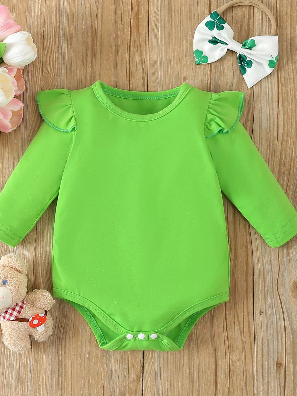 Green bodysuit beside clover-print bow headband