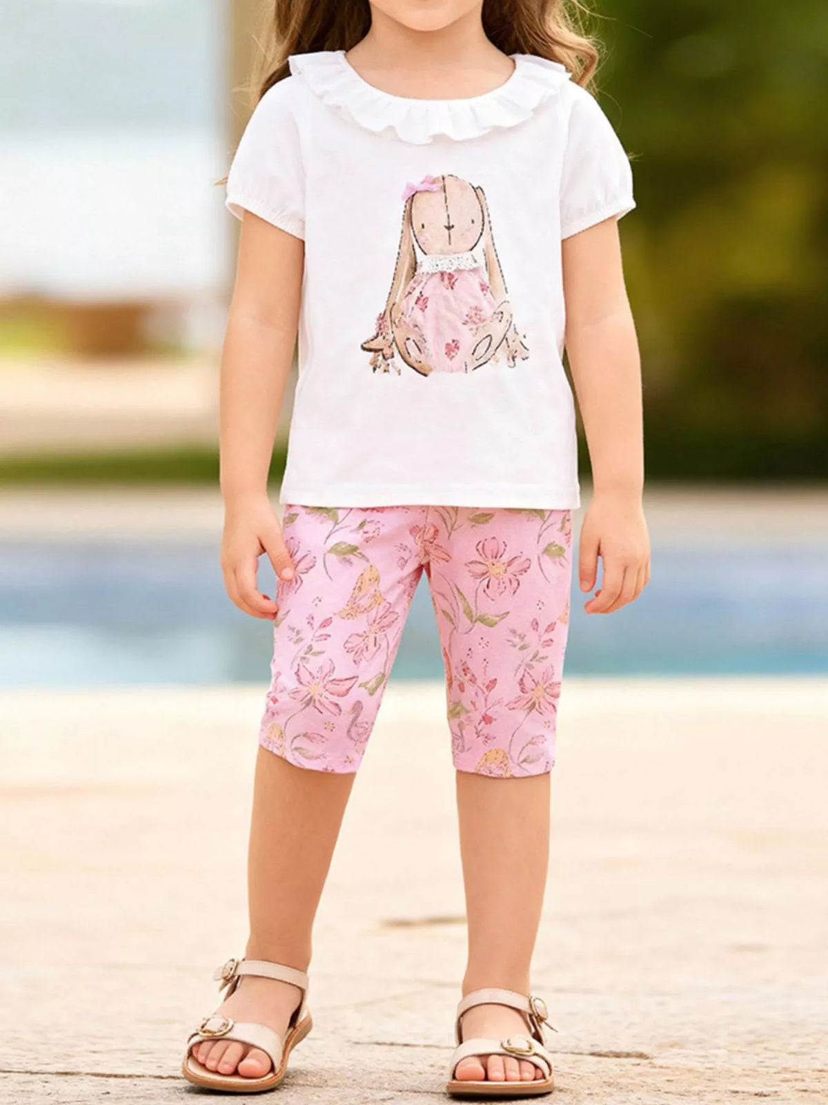 White bunny tee with a ruffled collar and pink floral shorts on a child
